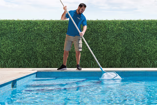 A man cleaning a pool with a mop.